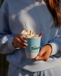 lady holding snowman hot chocolate drink with two hands while the drink looks aesthetic and beautiful