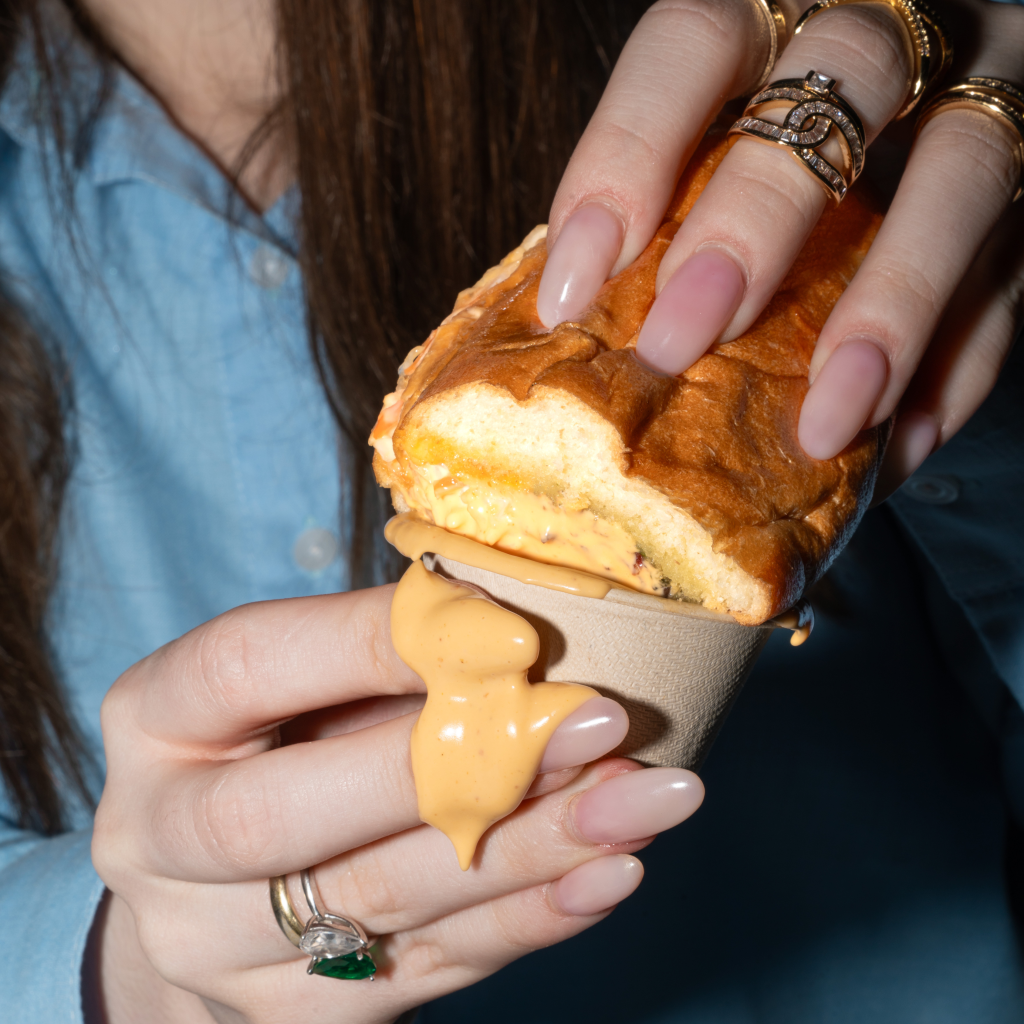 gustos deli sandwich being dipped into a sauce during the launch event of a cloud kitchen