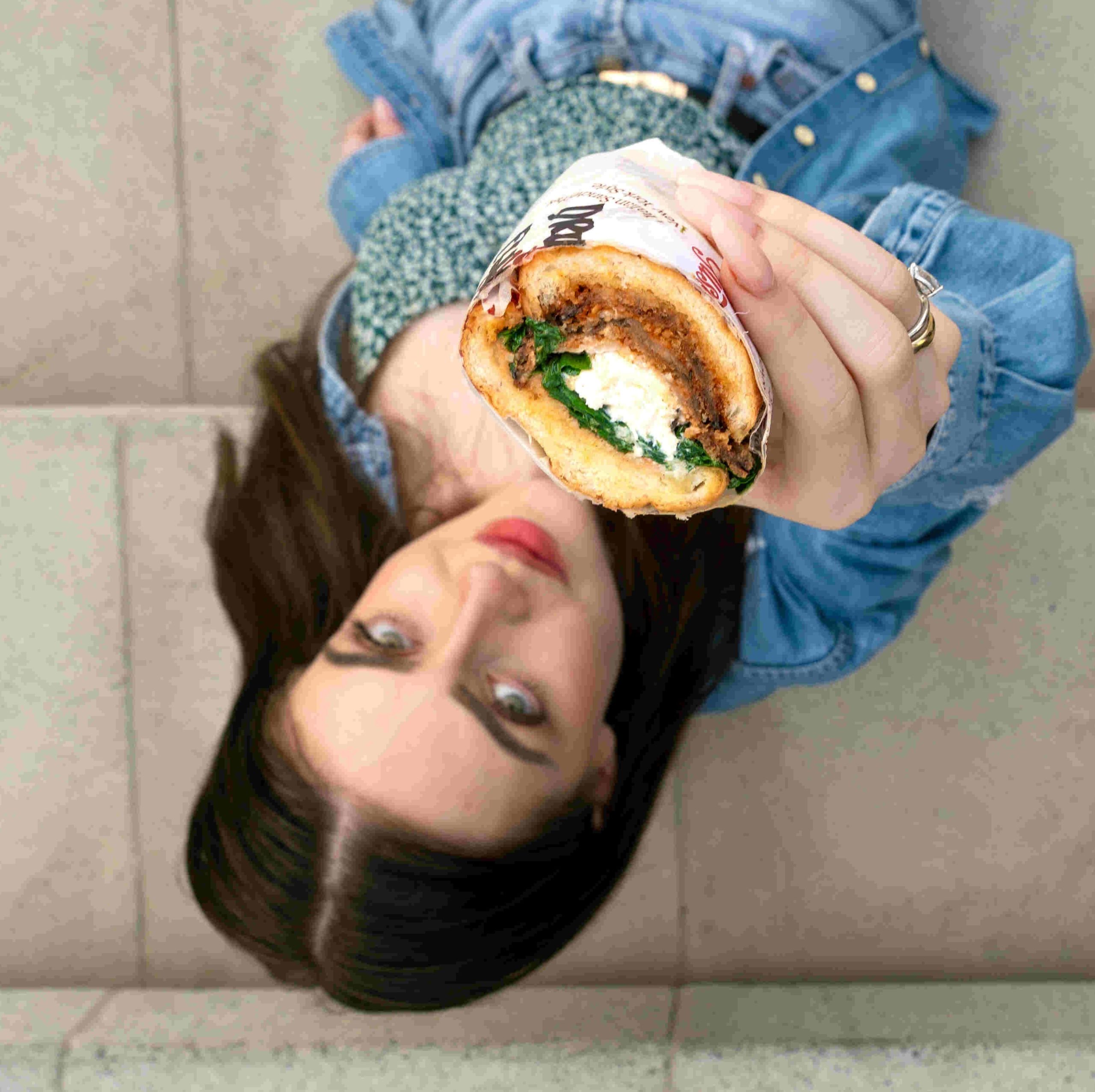 woman passing a cloud kitchen sandwich from gusto's in dubai to the camera