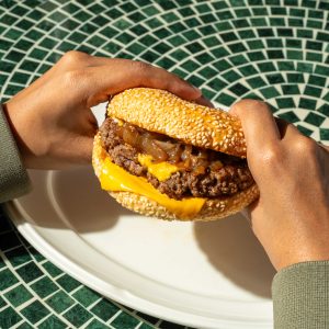 holding a wagyu burger in his hand for a menu photograph