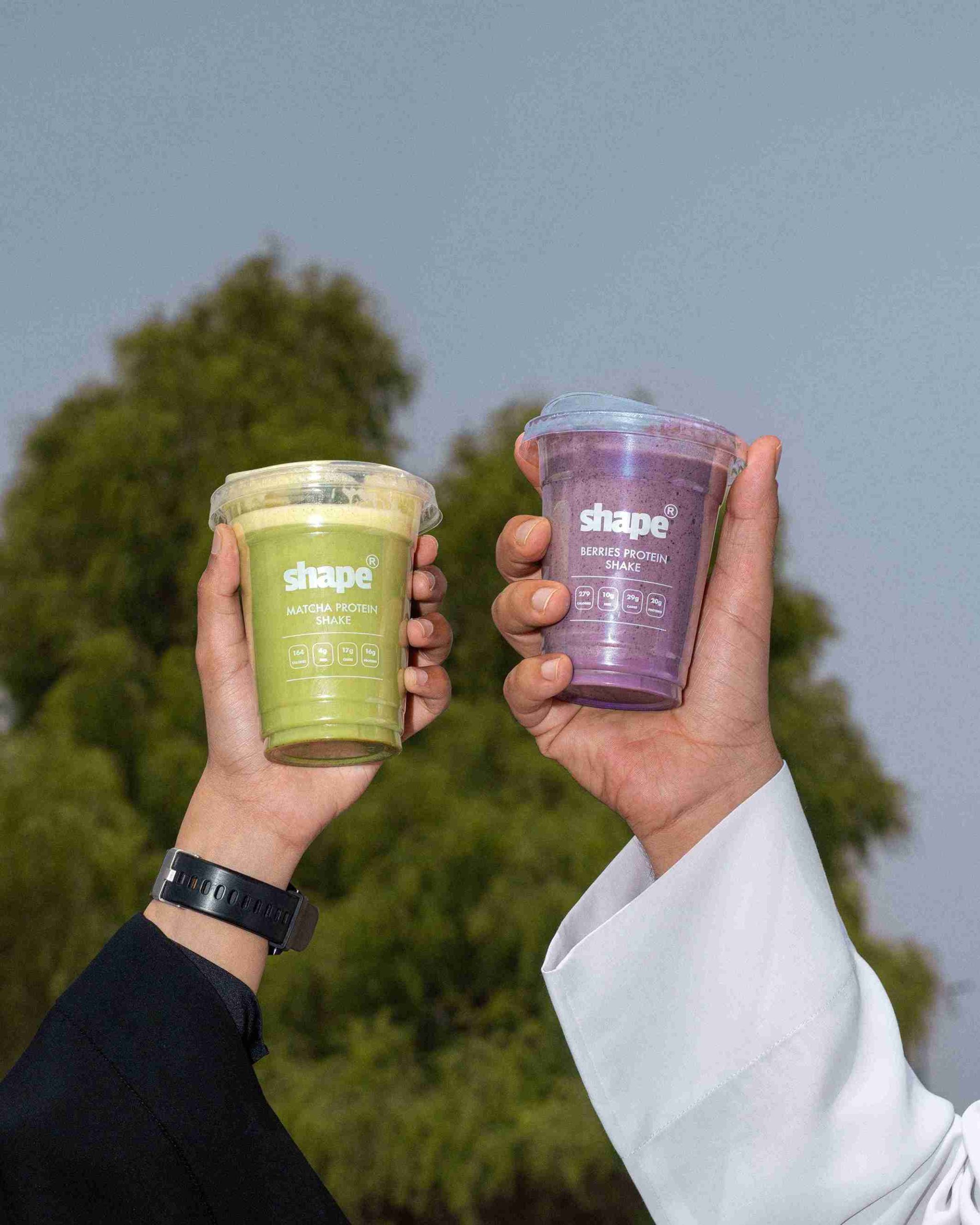 Two Shape protein shakes held up outdoors