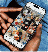 Hand holding a phone showing a restaurant Instagram feed grid