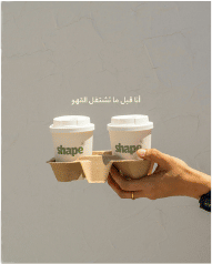 Hand holding two Shape takeaway coffees in a cup carrier